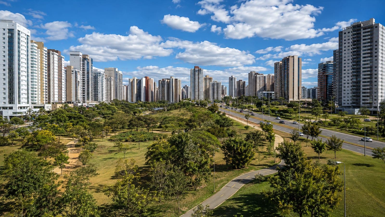 Vista de Águas Claras: torres residenciais ao fundo e o parque com árvores e ciclovia em primeiro plano.